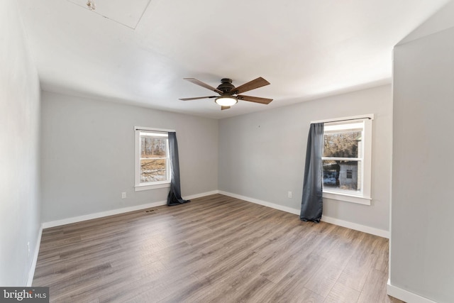 empty room with baseboards, wood finished floors, and a healthy amount of sunlight