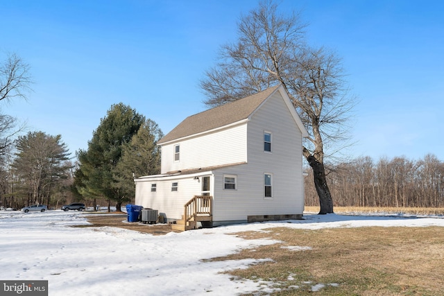 snow covered house featuring central AC unit