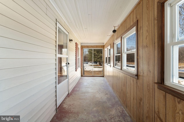 corridor featuring wood walls, wood ceiling, concrete flooring, and a sunroom