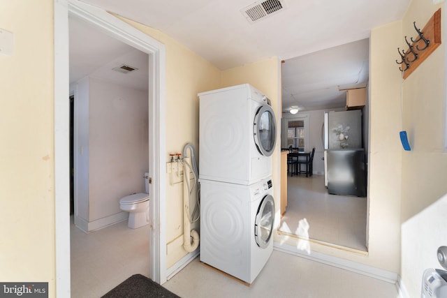 laundry room featuring laundry area, light floors, visible vents, and stacked washer / drying machine