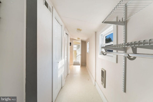 hall with baseboards, visible vents, and light floors