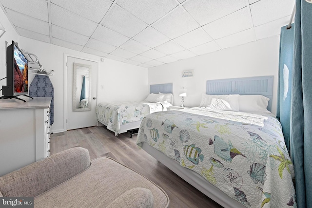 bedroom with light wood-type flooring and a paneled ceiling