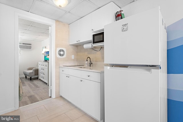 kitchen with white fridge, a paneled ceiling, sink, white cabinetry, and tasteful backsplash