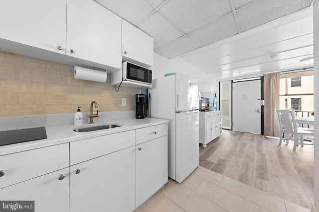 kitchen with sink, white cabinetry, white fridge, and built in microwave