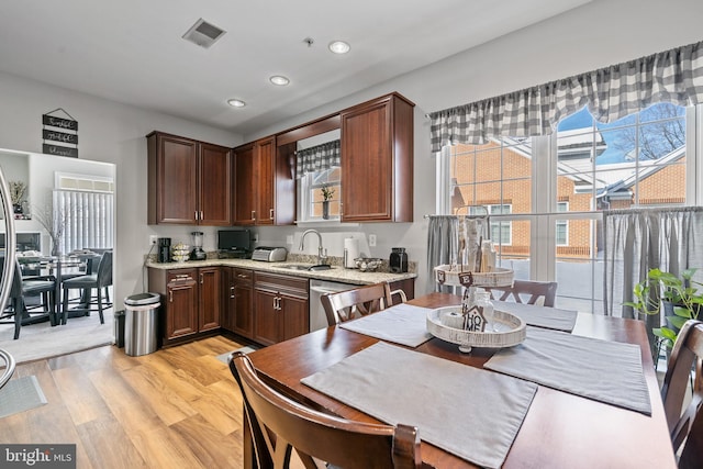 kitchen featuring sink, stainless steel dishwasher, light hardwood / wood-style floors, and light stone counters