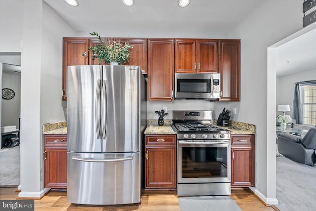 kitchen featuring light hardwood / wood-style flooring, light stone counters, and appliances with stainless steel finishes