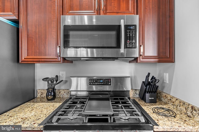 kitchen with light stone counters and appliances with stainless steel finishes