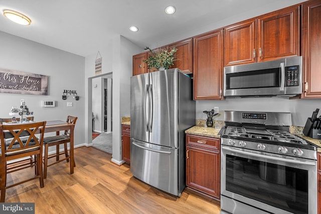 kitchen with stainless steel appliances, light wood-type flooring, and light stone countertops