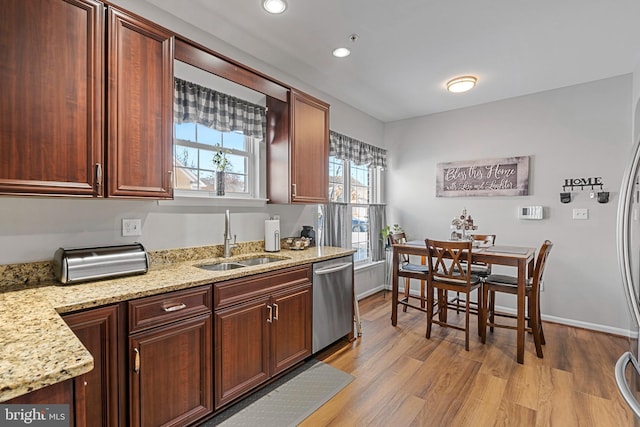 kitchen featuring light stone countertops, stainless steel dishwasher, light hardwood / wood-style flooring, and sink