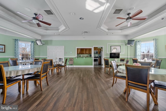 dining area with ornamental molding, ceiling fan, a tray ceiling, and dark hardwood / wood-style flooring