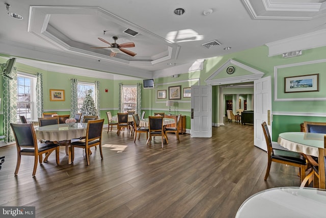 dining space featuring ornamental molding, a raised ceiling, ceiling fan, and dark hardwood / wood-style flooring