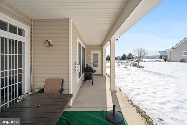 snow covered patio with a porch, cooling unit, and grilling area