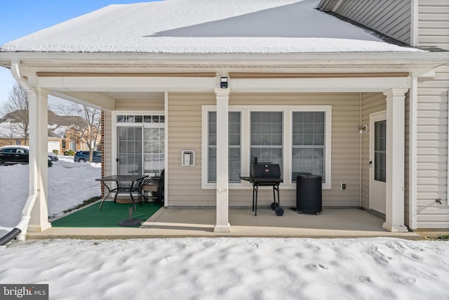 snow covered back of property featuring a porch