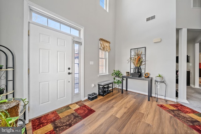 foyer entrance with a towering ceiling, a wealth of natural light, and light hardwood / wood-style flooring