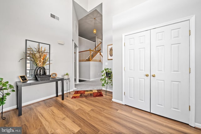 foyer entrance featuring hardwood / wood-style floors and a towering ceiling