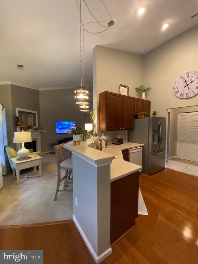 kitchen with decorative light fixtures, kitchen peninsula, sink, stainless steel fridge with ice dispenser, and dark hardwood / wood-style flooring