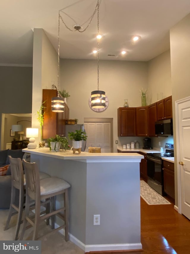 kitchen with kitchen peninsula, dark wood-type flooring, stainless steel appliances, and a kitchen bar