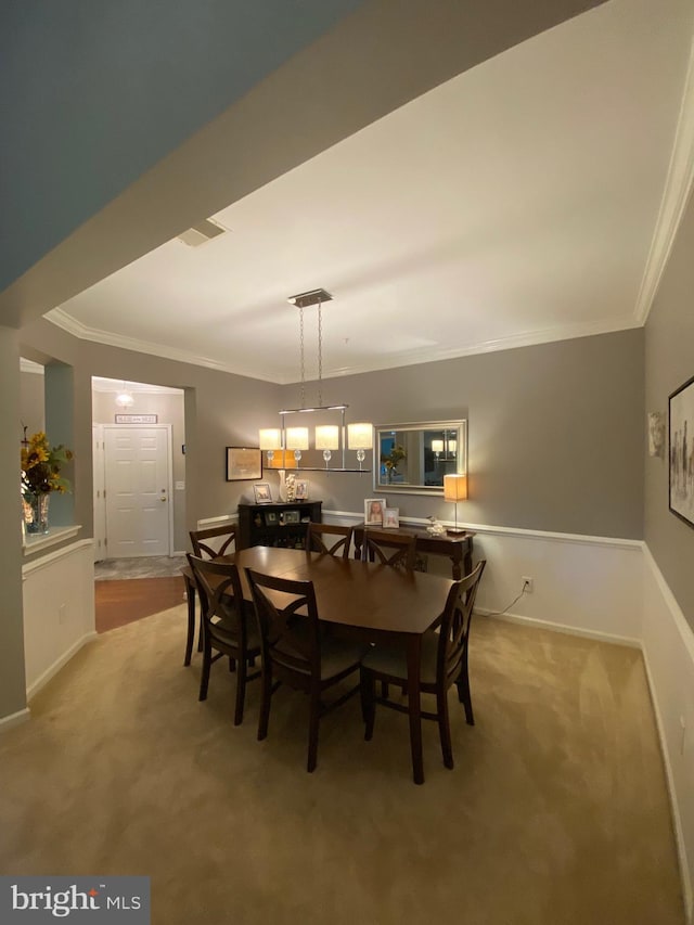 carpeted dining space featuring crown molding