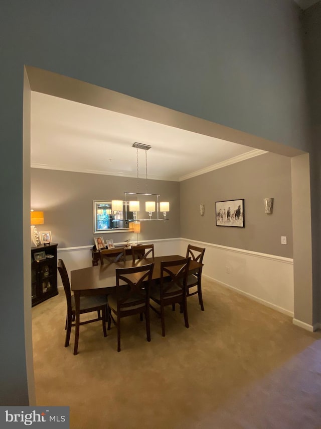 dining room featuring ornamental molding, an inviting chandelier, and carpet flooring