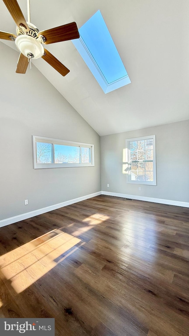 unfurnished living room featuring ceiling fan, vaulted ceiling with skylight, and dark hardwood / wood-style floors