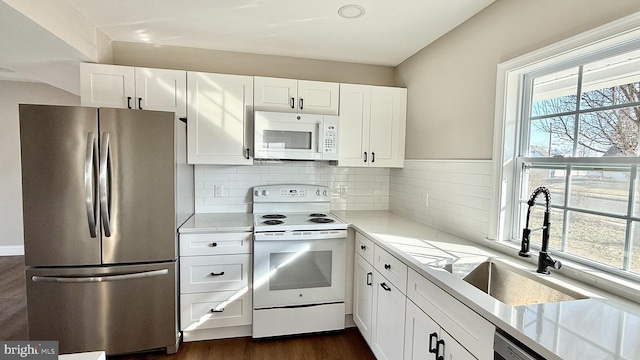 kitchen featuring white appliances, dark hardwood / wood-style flooring, decorative backsplash, sink, and white cabinetry