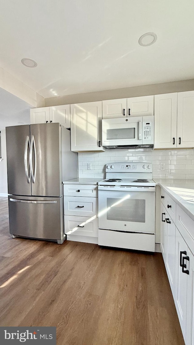 kitchen with white appliances, dark wood-type flooring, white cabinetry, and backsplash