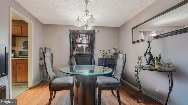 dining area featuring a textured ceiling, hardwood / wood-style floors, and a chandelier