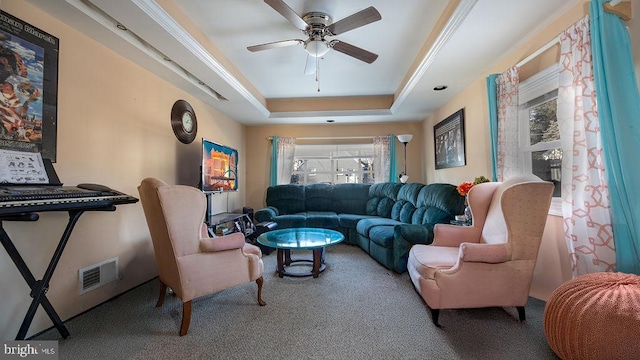 carpeted living room with a raised ceiling, ceiling fan, and a wealth of natural light