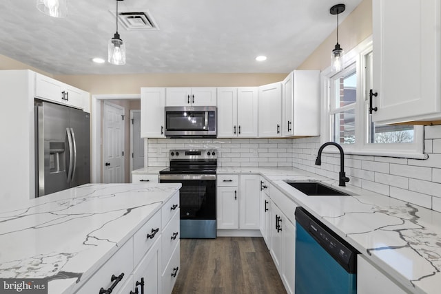 kitchen with sink, decorative light fixtures, white cabinetry, backsplash, and appliances with stainless steel finishes