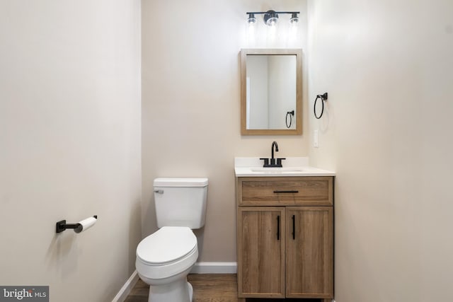 bathroom featuring wood-type flooring, vanity, and toilet