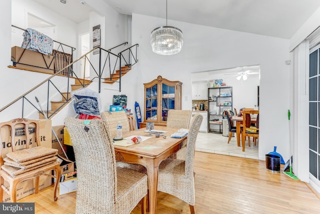 dining space with ceiling fan with notable chandelier and light hardwood / wood-style floors