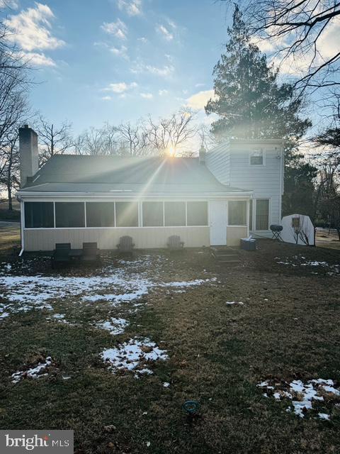 snow covered rear of property with a sunroom