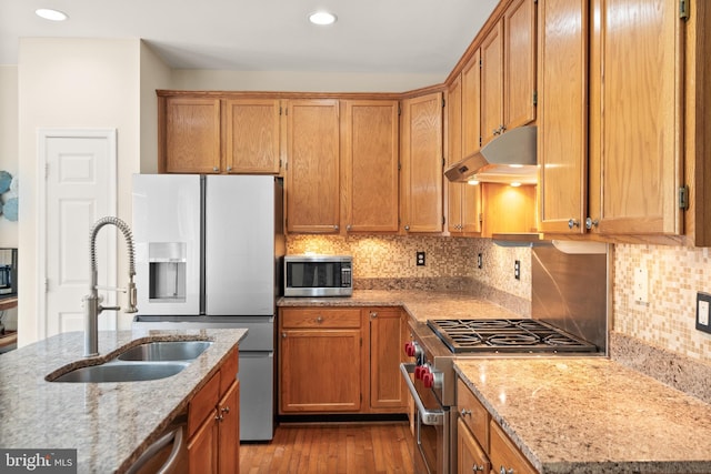 kitchen featuring light stone countertops, appliances with stainless steel finishes, sink, and tasteful backsplash