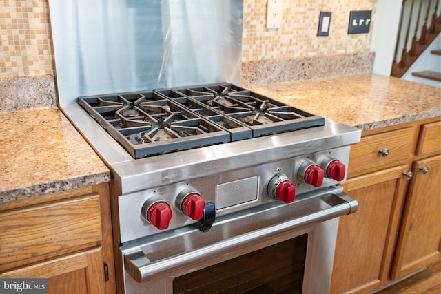 room details with light stone countertops, designer range, and tasteful backsplash