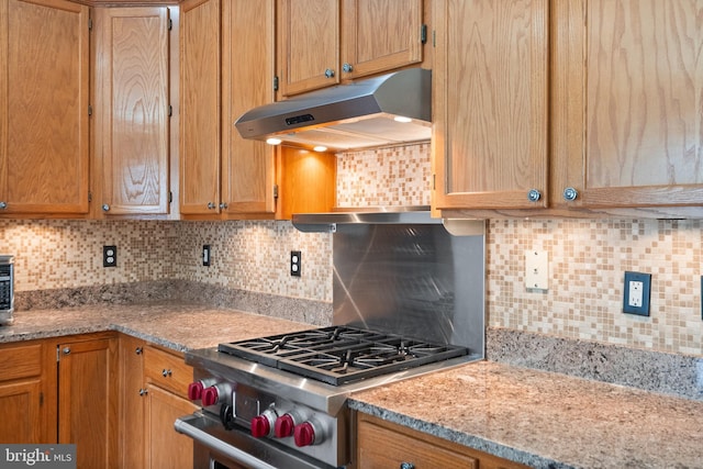 kitchen featuring decorative backsplash, light stone countertops, and range