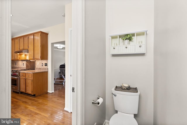 bathroom with hardwood / wood-style flooring, toilet, backsplash, and vanity