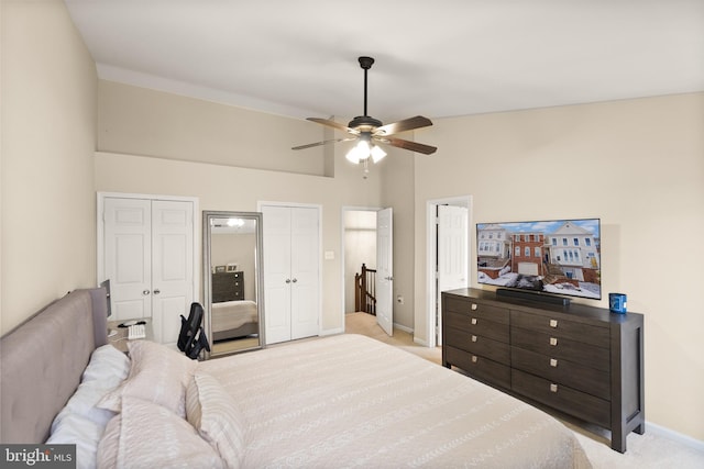 carpeted bedroom featuring ceiling fan, lofted ceiling, and two closets