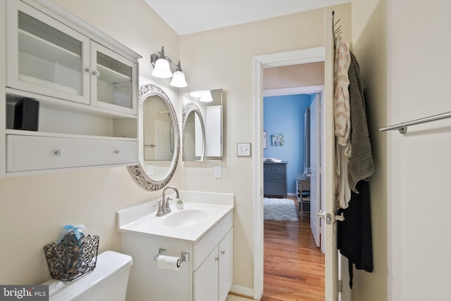 bathroom with toilet, hardwood / wood-style floors, and vanity