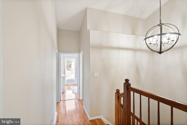 corridor featuring light wood-type flooring and an inviting chandelier