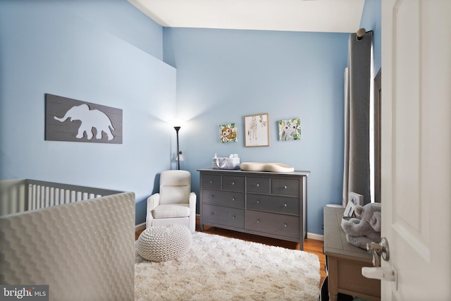 bedroom with hardwood / wood-style flooring and a nursery area