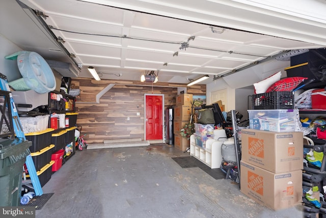 garage featuring a garage door opener and wooden walls