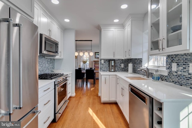 kitchen featuring white cabinetry, appliances with stainless steel finishes, decorative light fixtures, and sink