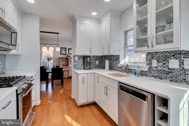 kitchen featuring white cabinetry, pendant lighting, light hardwood / wood-style flooring, and stainless steel appliances