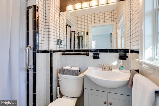 bathroom with vanity, toilet, and tile walls