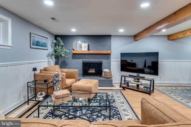 living room featuring beamed ceiling, hardwood / wood-style flooring, and a fireplace