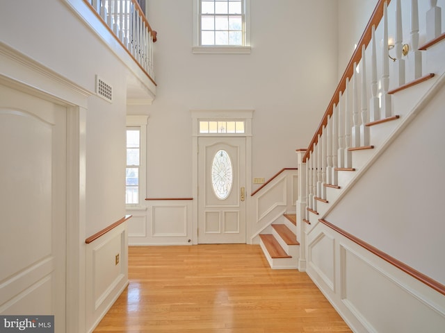 entryway featuring light hardwood / wood-style floors, a towering ceiling, and a healthy amount of sunlight