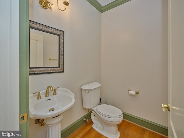 bathroom featuring toilet, sink, ornamental molding, and hardwood / wood-style floors