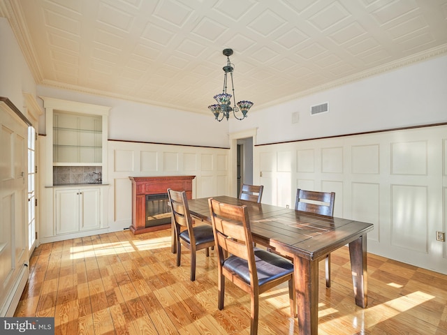 dining room featuring light hardwood / wood-style flooring, crown molding, and a notable chandelier