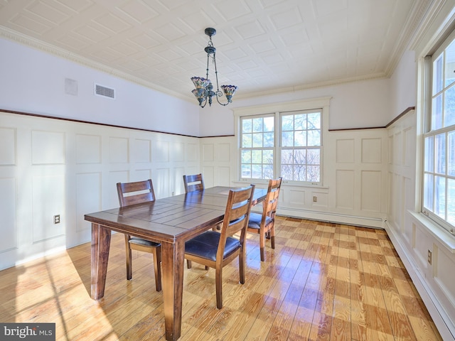 dining room with a baseboard heating unit, ornamental molding, a chandelier, and light wood-type flooring