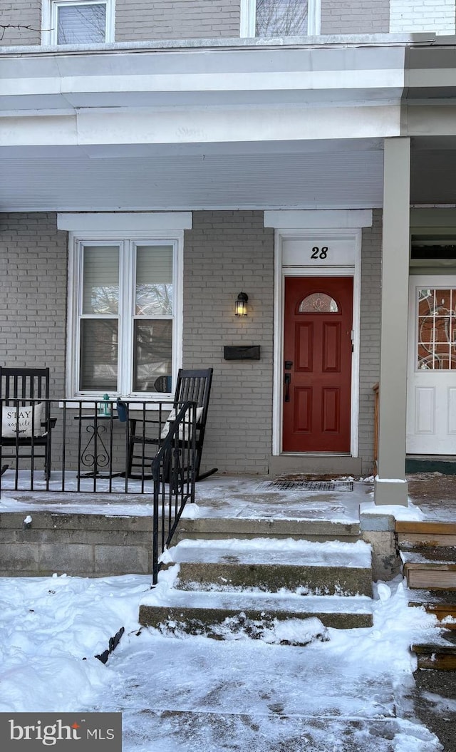 snow covered property entrance featuring a porch